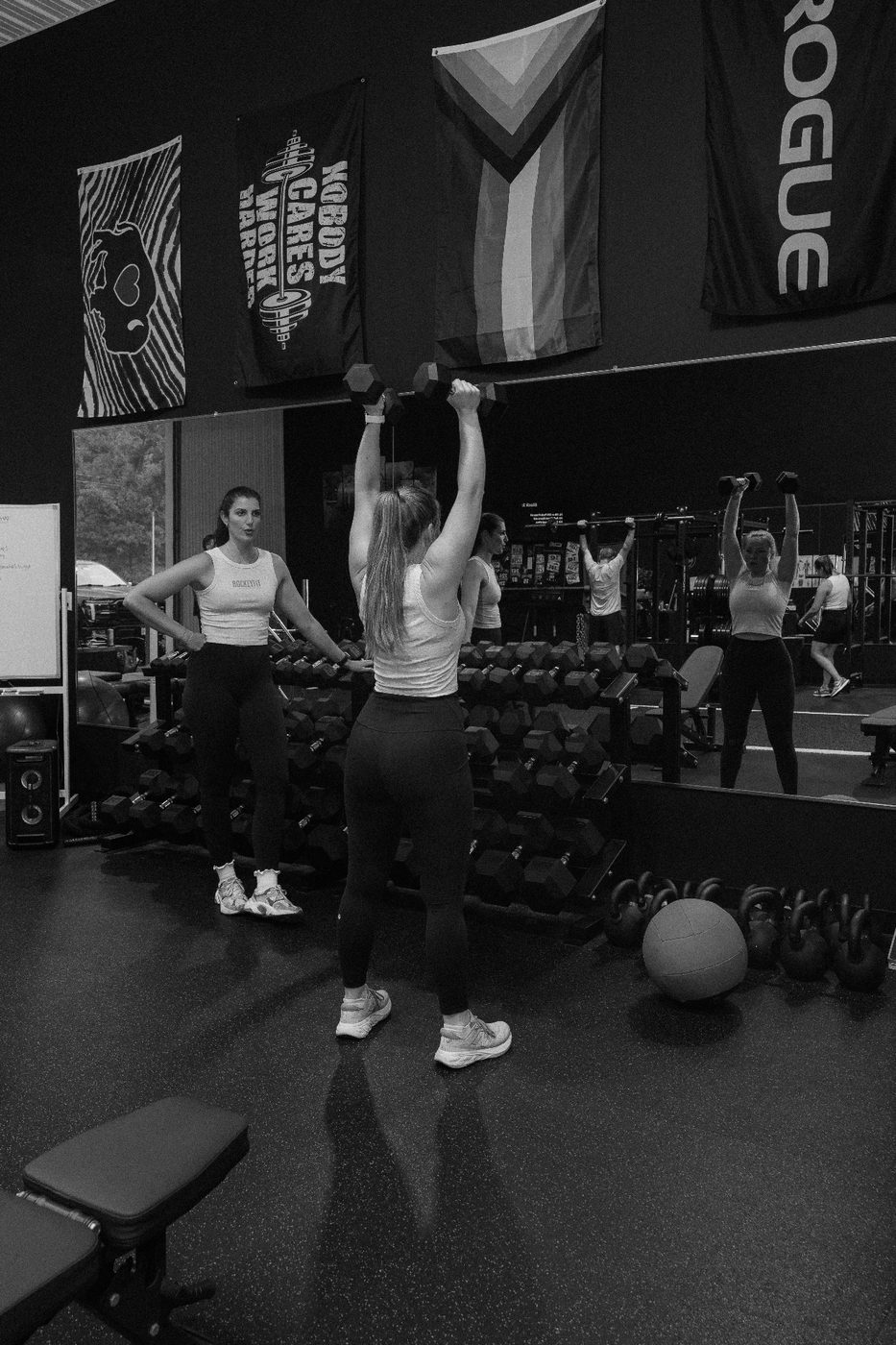 Members pressing dumbbells overhead in a coached RockeyFit group session