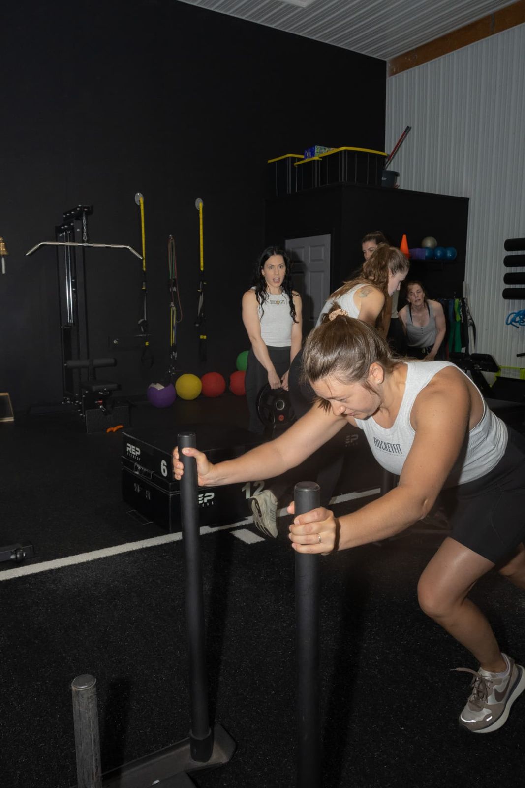 Member pushing a weighted sled during a RockeyFit small group session