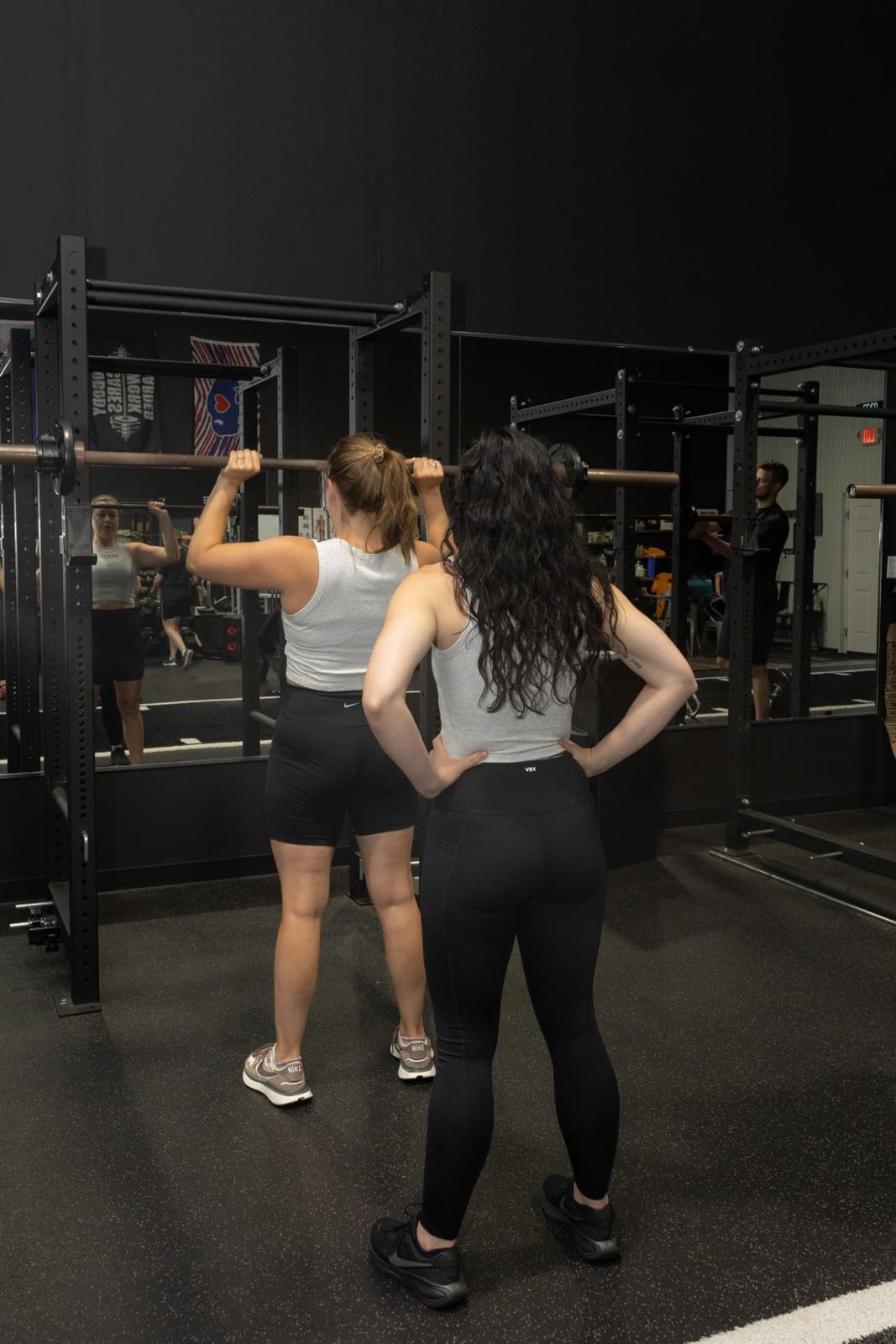 Coach teaching barbell squat setup in the RockeyFit rack area